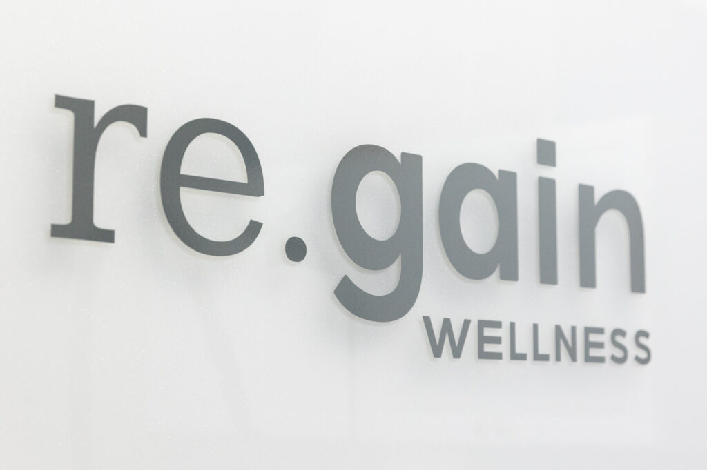 Sign that says 're.gain wellness' on wall of a wellness center in Leawood
