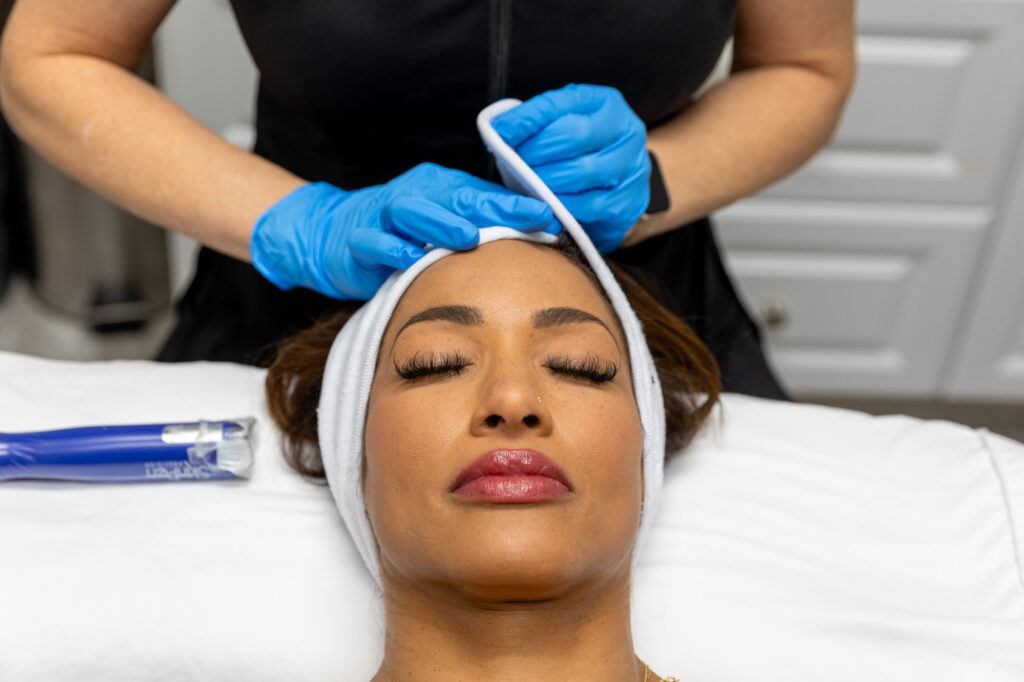 woman with towel on head as medical professional performs one of the facials in Overland Park