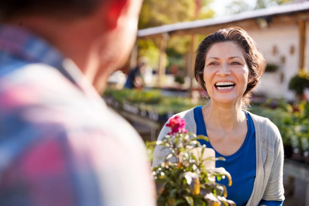 A mature woman smiles while her husband gives her a flower after she receives vaginal rejuvenation in Leawood