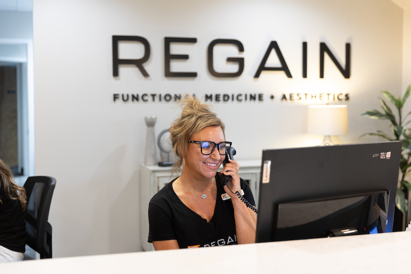 Picture of friendly Regain provider at front desk answering phone to the Sexual Health Clinic in Kansas City