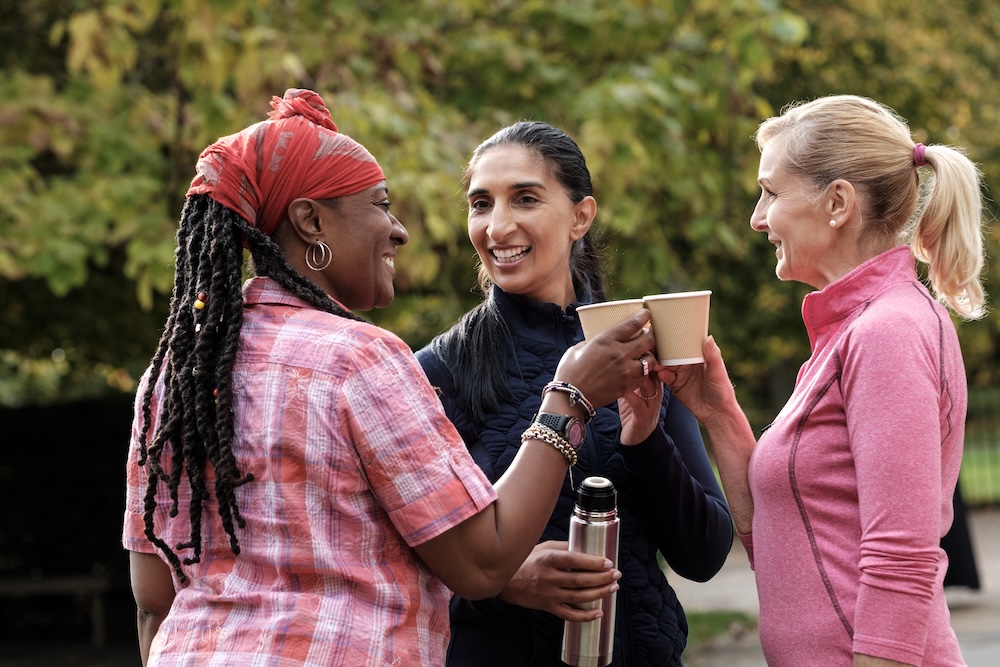 Menopausal women drinking coffee outside and discussing the incredible benefits they are receiving from hormone optimization near Overland Park