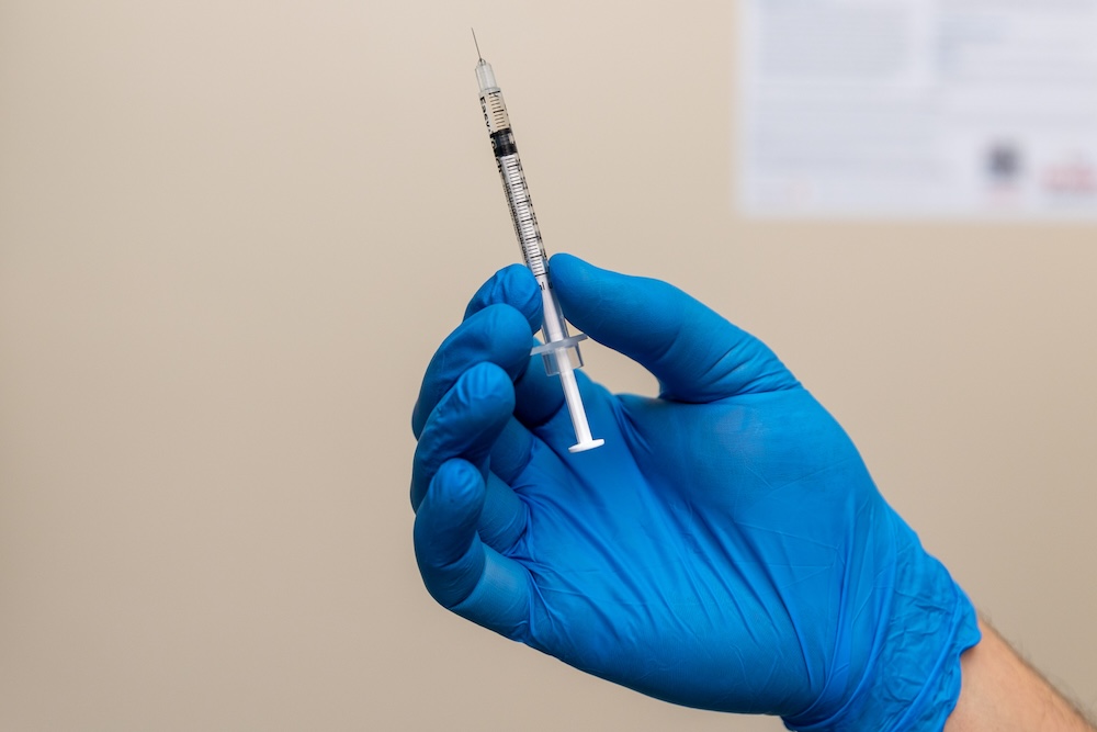 Gloved hand holds syringe and needle filled with NAD+ therapy in Leawood. An injection or IV that promotes longevity, immunity, and energy