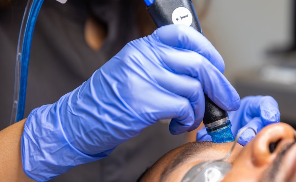 Provider places handheld device for Hydrafacial treatment in Overland Park on patient's forehead.