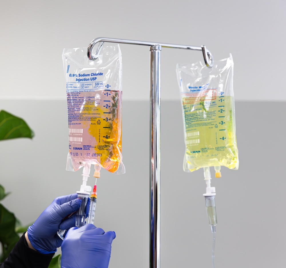 IV infusion bags filled with glutathione and NAD+ for anti-aging in Leawood. The provider is hooking them to tubes which will deliver these nutrients directly into the patient's bloodstream.