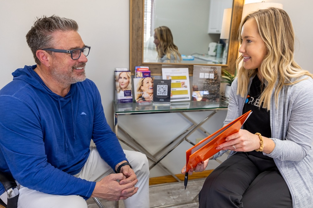 Man and provider sit in treatment room to discuss which neuromodulator will work best for him. At Regain, he can choose from Daxxify, Dysport, or Botox in Leawood.
