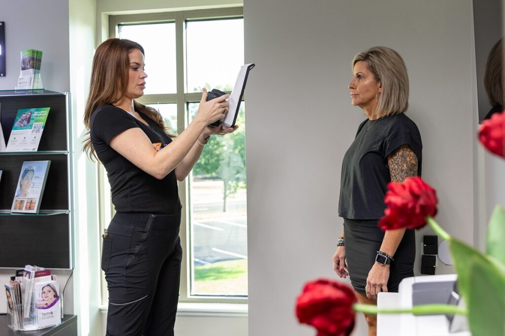 Patient stands and poses while her provider takes her picture. They are tracking the patient's progress with different treatments offered at this wellness clinic near Overland Park.